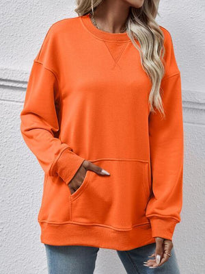 a woman wearing an orange sweatshirt and jeans