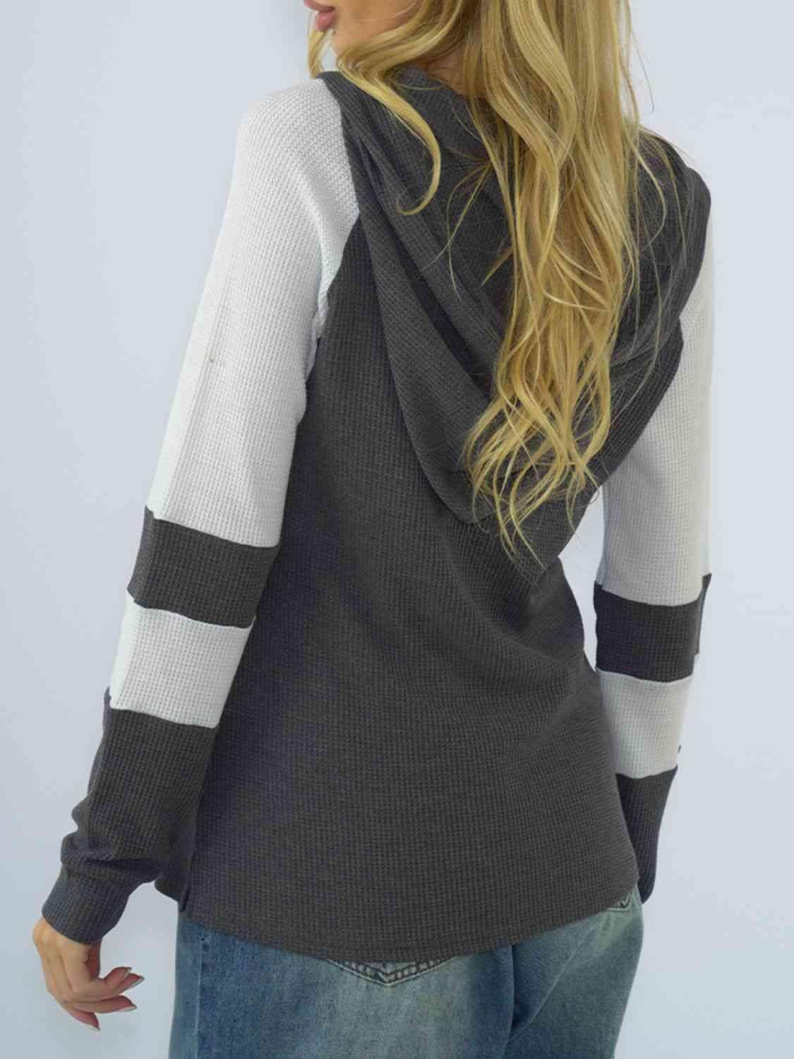 a woman with long blonde hair wearing a black and white sweater