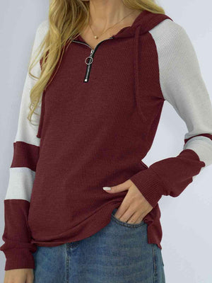 a woman wearing a maroon and white hoodie