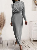 a woman in a grey dress is standing on a wooden floor