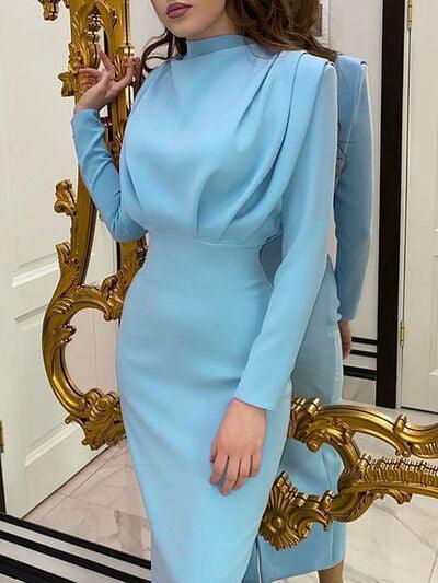a woman in a blue dress standing in front of a mirror