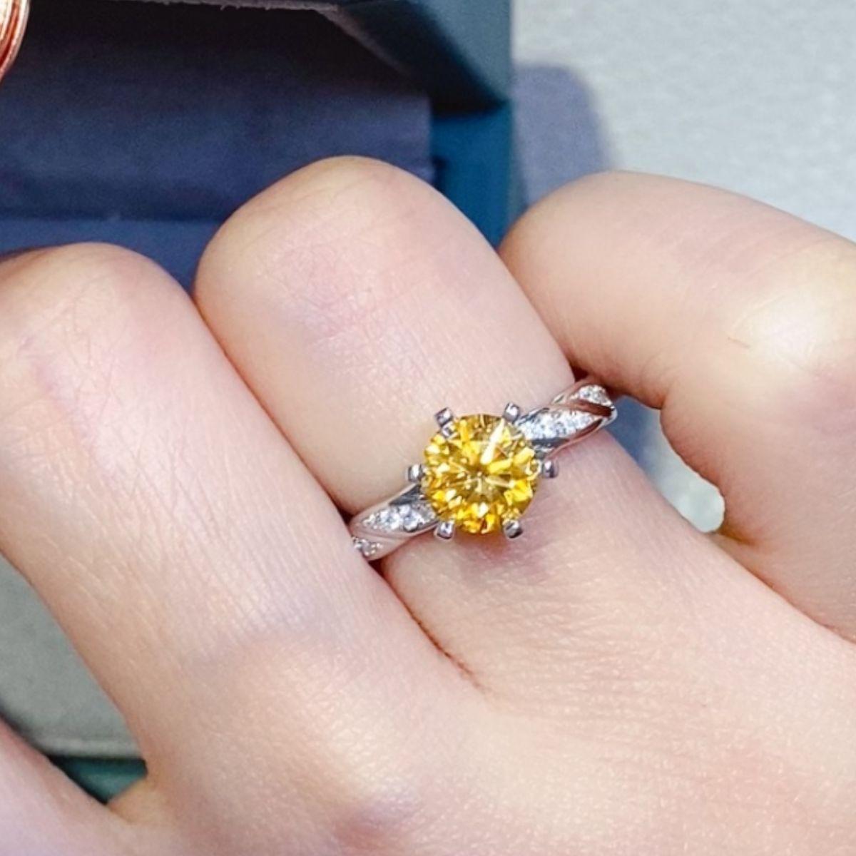 a woman's hand holding a yellow diamond ring