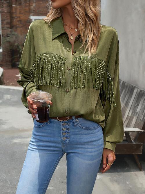 a woman in a green shirt and jeans holding a drink