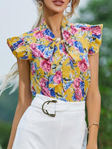 a woman wearing a yellow floral shirt and white skirt