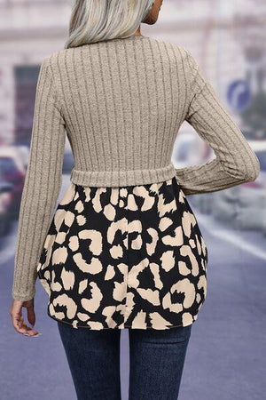 a woman wearing a sweater and a leopard print skirt