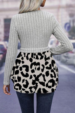 a woman in a grey sweater and black and white leopard print skirt