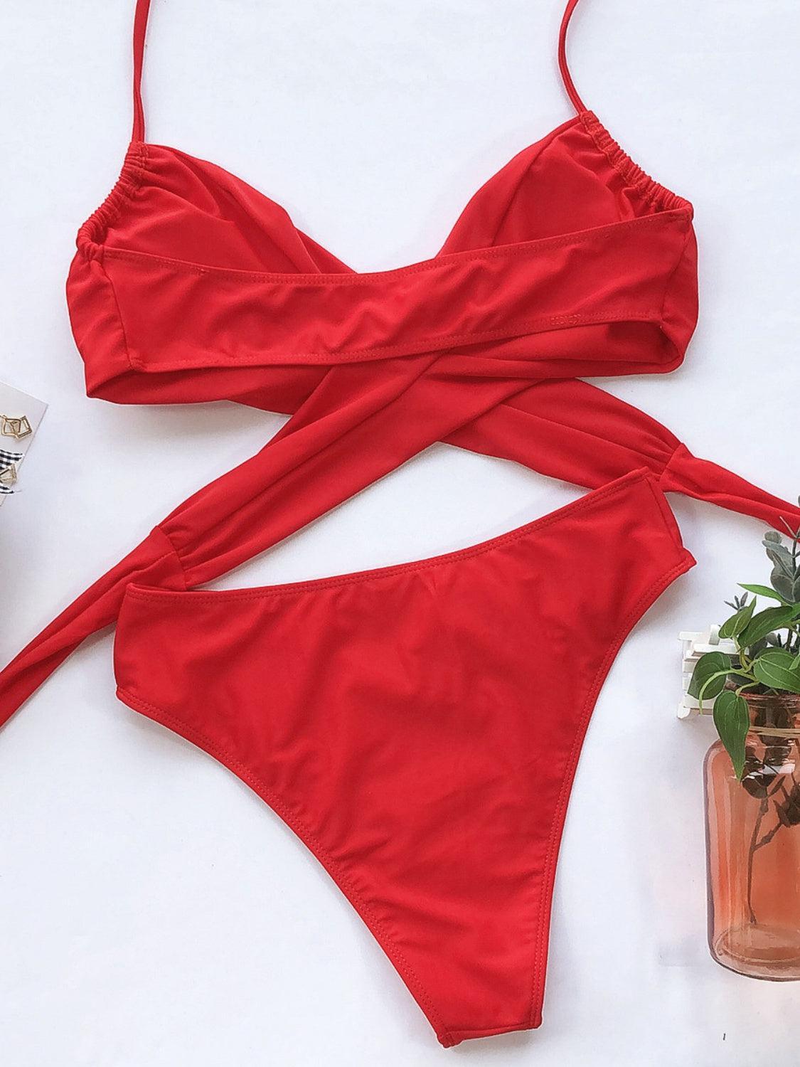 a red one piece swimsuit next to a potted plant