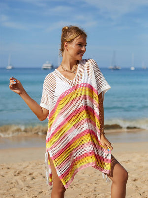 a woman standing on a beach wearing a colorful ponchy