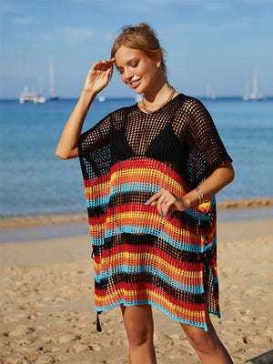 a woman standing on a beach holding a colorful blanket