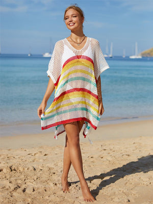 a woman standing on a beach wearing a colorful dress