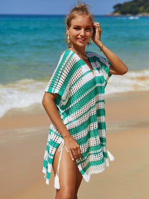 a woman in a green and white cover up on the beach