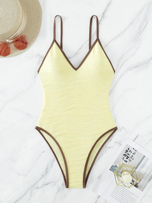 a yellow one piece swimsuit next to a hat