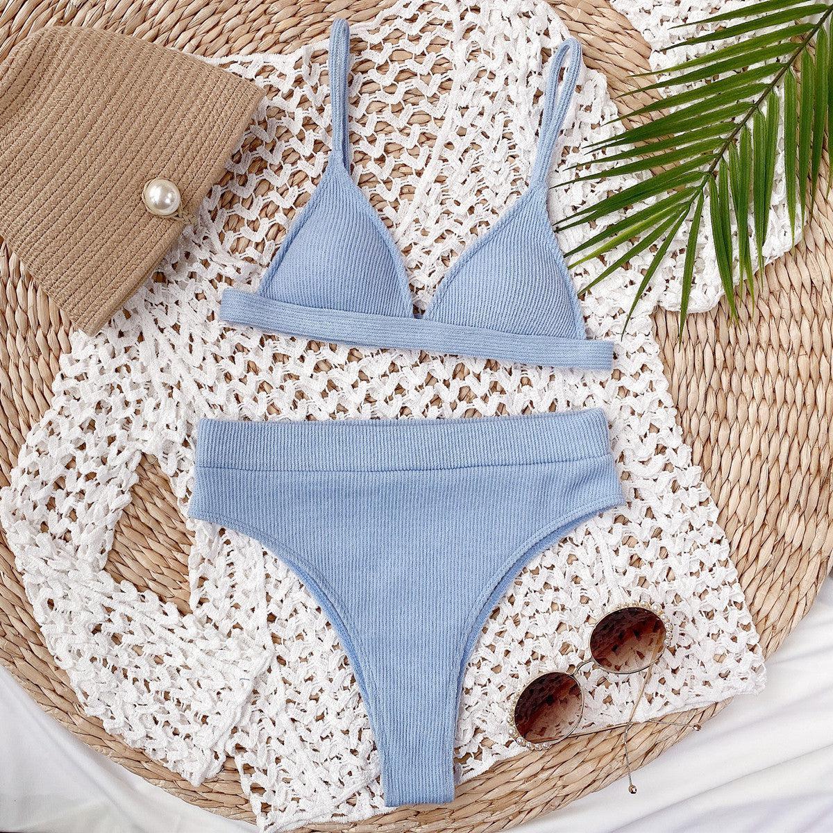 a woman's blue swimsuit and hat on a wicker mat