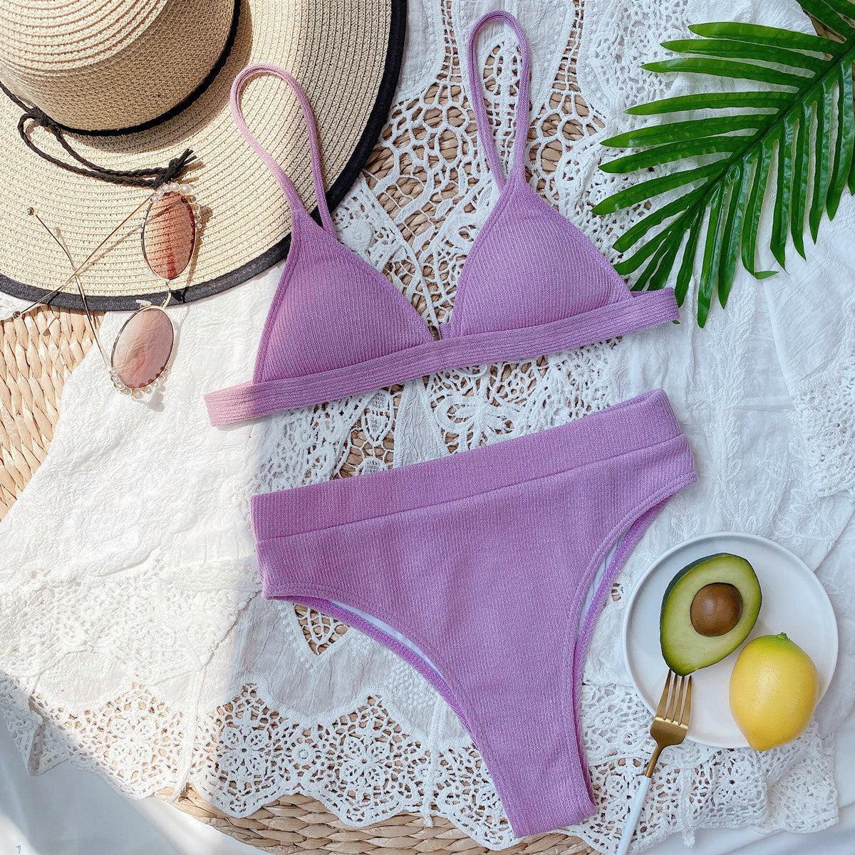 a woman's purple bikini top and a plate of fruit and a straw hat