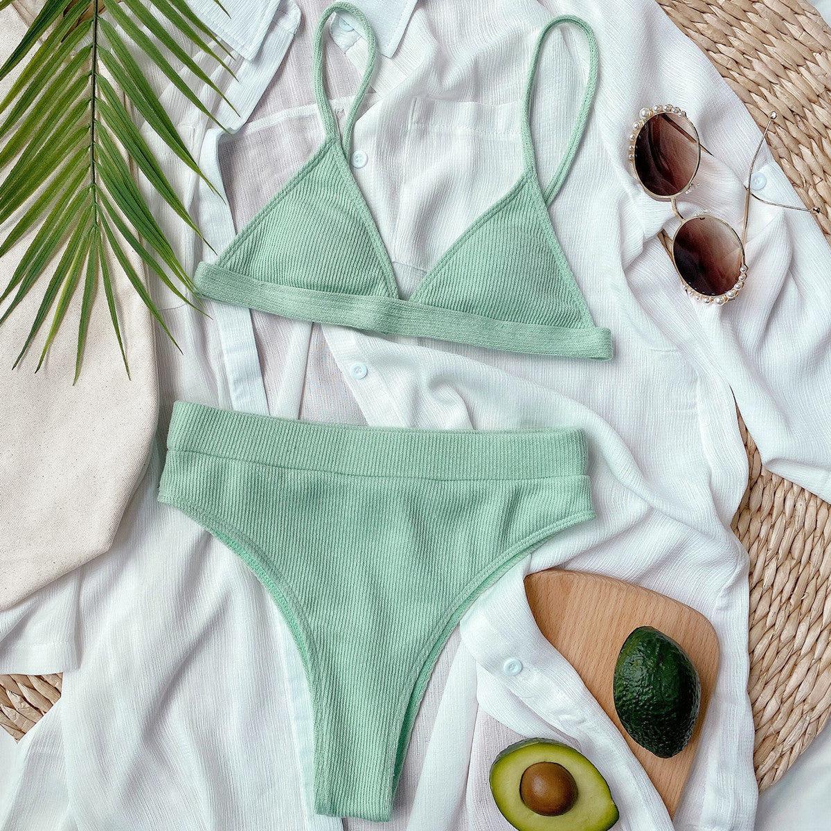 a woman's green bikinisuit with sunglasses, avocado, and a