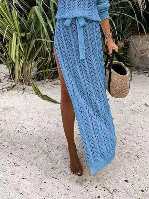 a woman in a blue knitted dress walking on the beach
