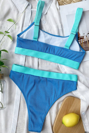 a woman's blue and green bikinisuit next to a cutting board