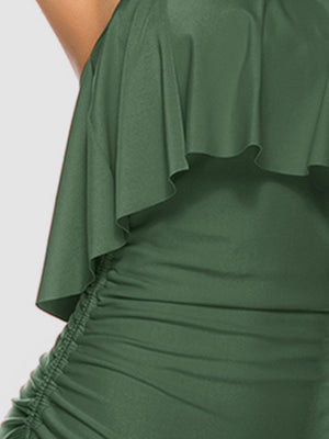 a woman wearing a green dress with ruffled shoulders