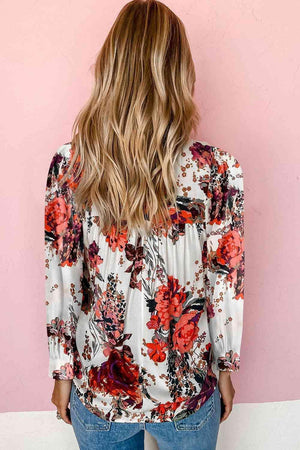 a woman standing against a pink wall wearing a floral blouse