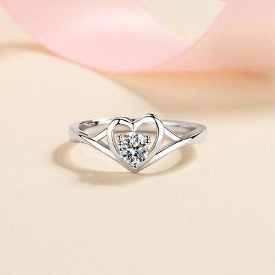 a heart shaped diamond ring with a pink ribbon in the background