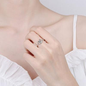 a woman wearing a ring with a heart on it