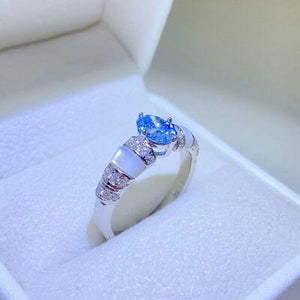 a ring with a blue topaz sits in a white box