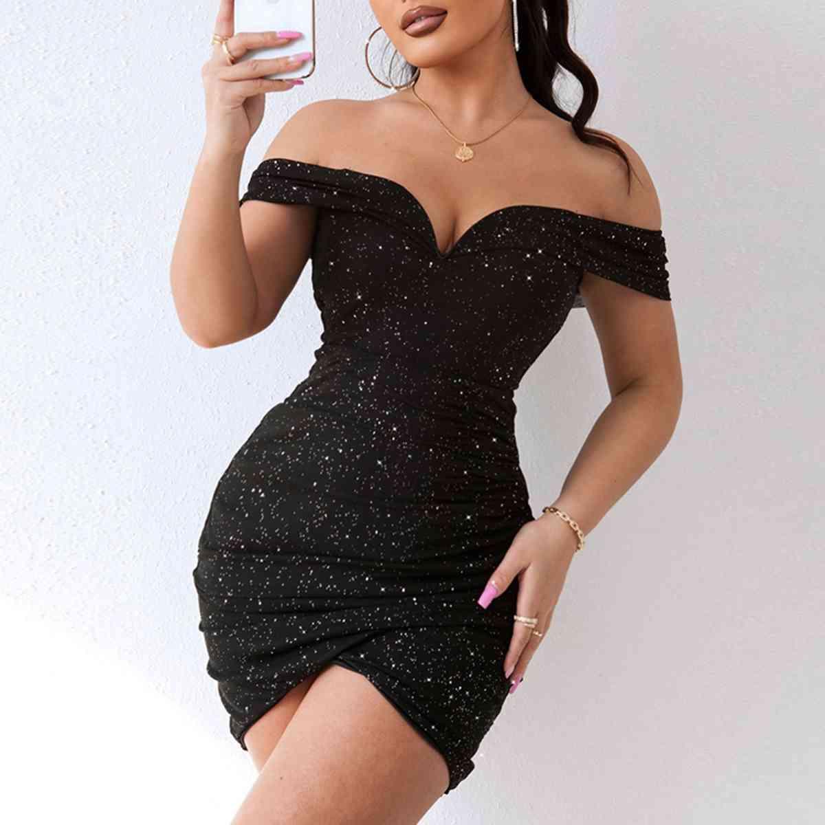 a woman in a short black dress holding a glass of wine