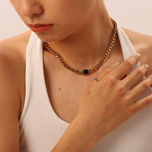 a woman wearing a white tank top and a gold chain necklace