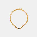 a gold chain necklace with a black bea