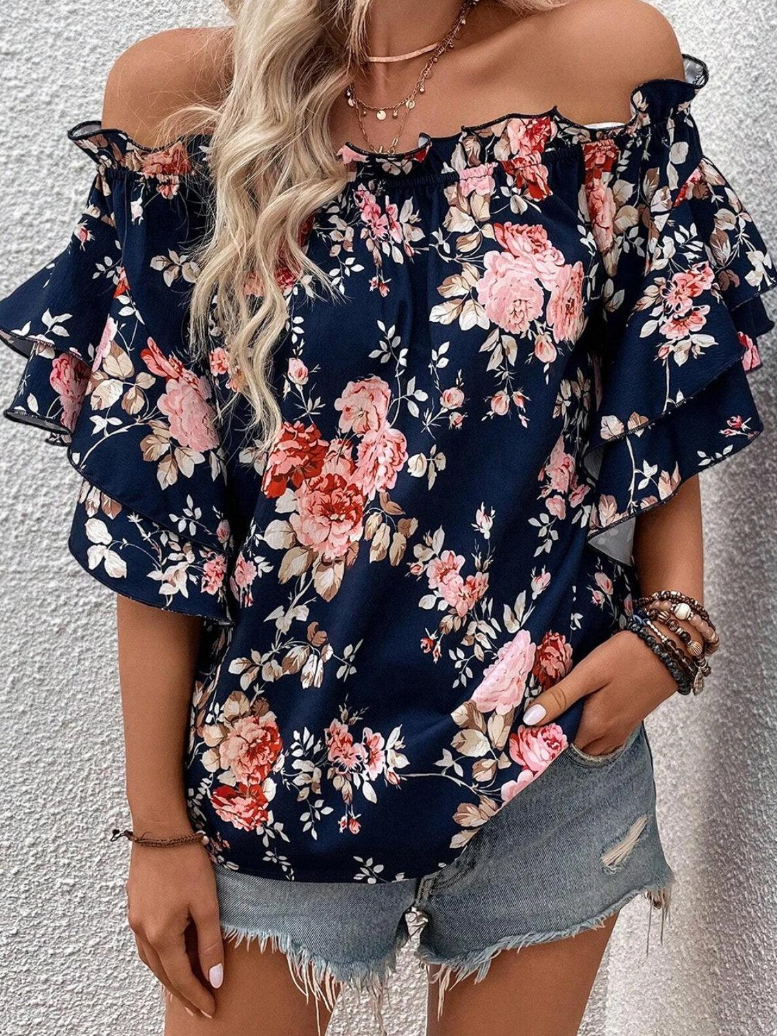 a woman wearing a floral top and denim shorts