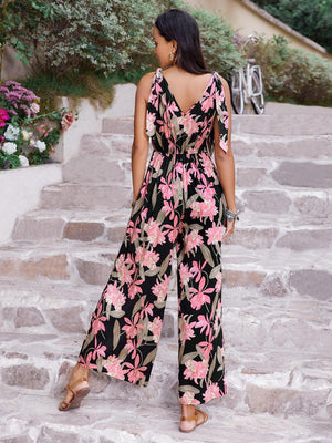 a woman in a black and pink floral print jumpsuit