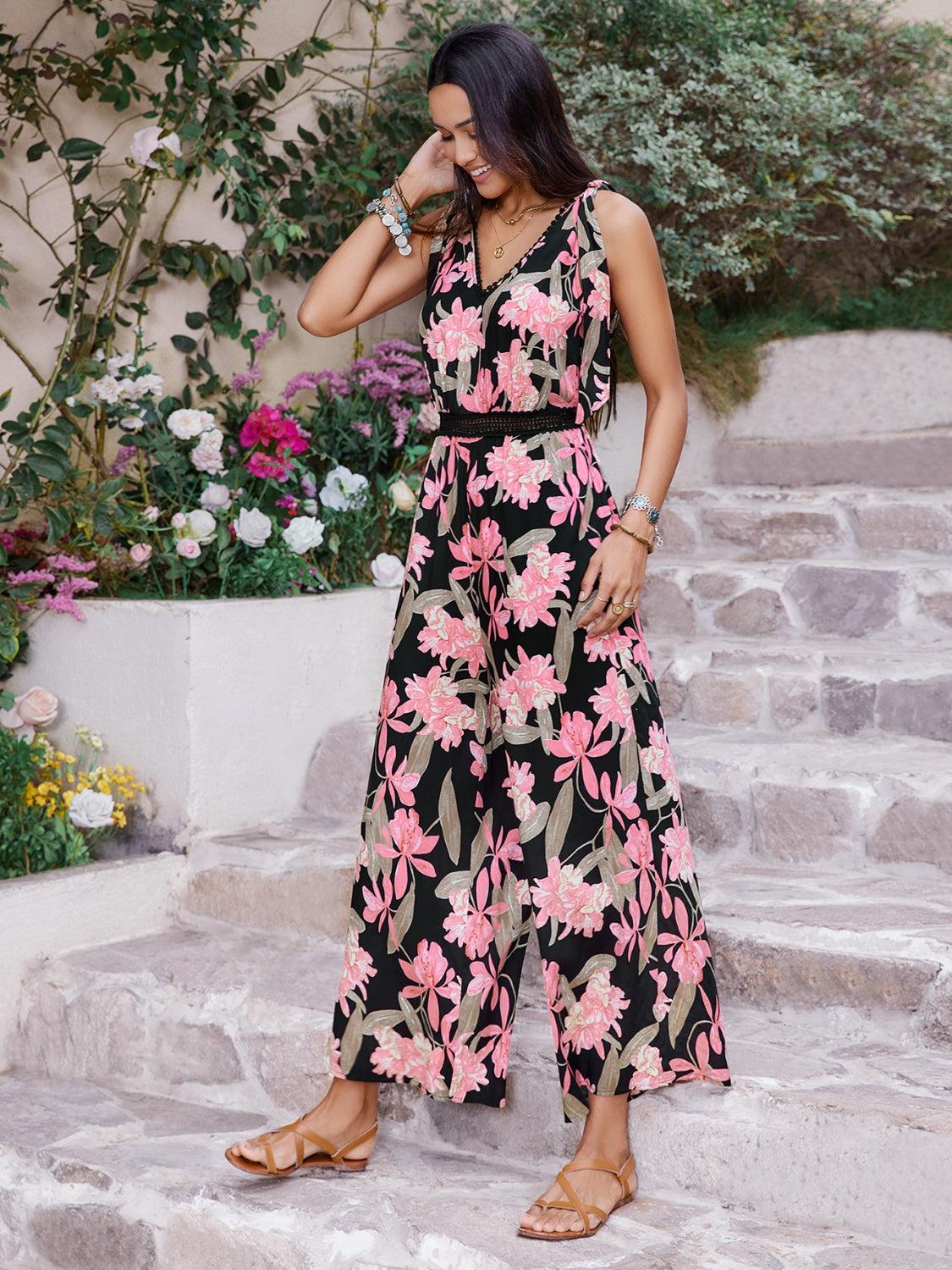 a woman in a black and pink floral print jumpsuit