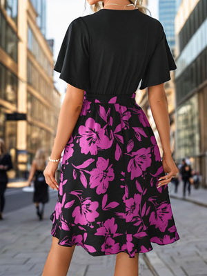 a woman in a black and pink dress is walking down the street