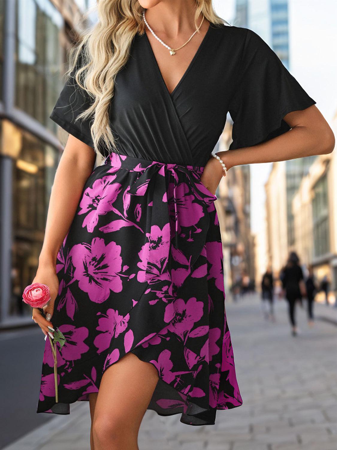 a woman in a black and pink dress is walking down the street