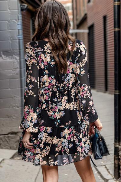 a woman in a black floral dress is walking down the street