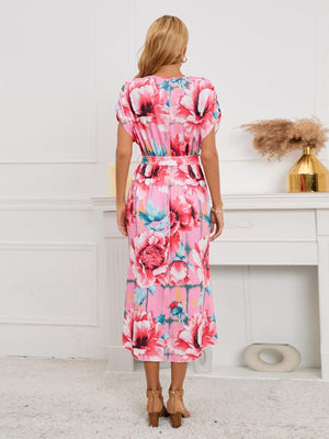 a woman standing in front of a fireplace wearing a pink floral dress