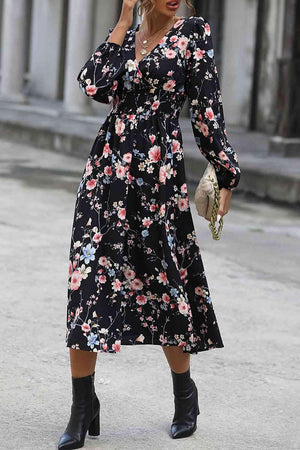 a woman in a black floral dress talking on a cell phone