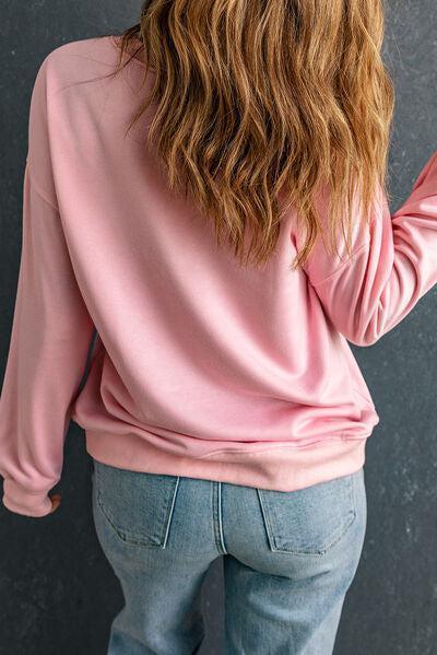 a woman wearing a pink sweatshirt and jeans