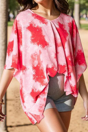 a woman walking down a dirt road wearing a red and white top