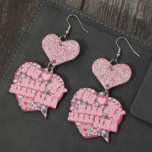 a pair of pink heart shaped earrings sitting on top of a table