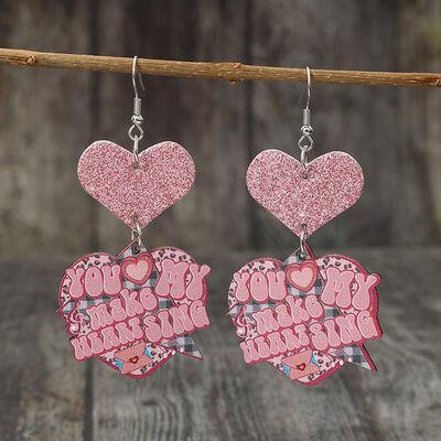 a pair of pink heart shaped earrings hanging from a clothes line