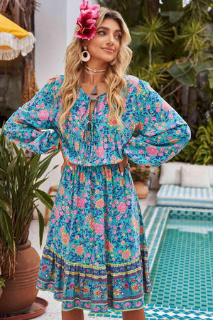 a woman standing in front of a pool wearing a blue floral dress