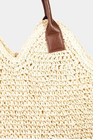 a crocheted straw bag with a brown leather handle