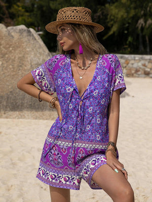 a woman in a purple dress and hat on the beach