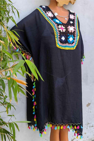 a woman's black top with colorful pom poms
