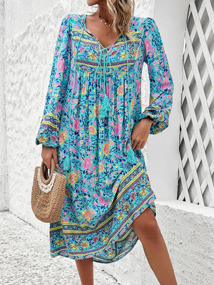 a woman in a blue floral dress holding a straw bag