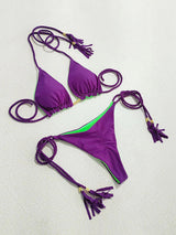 two purple bikinis with tassels on a white surface