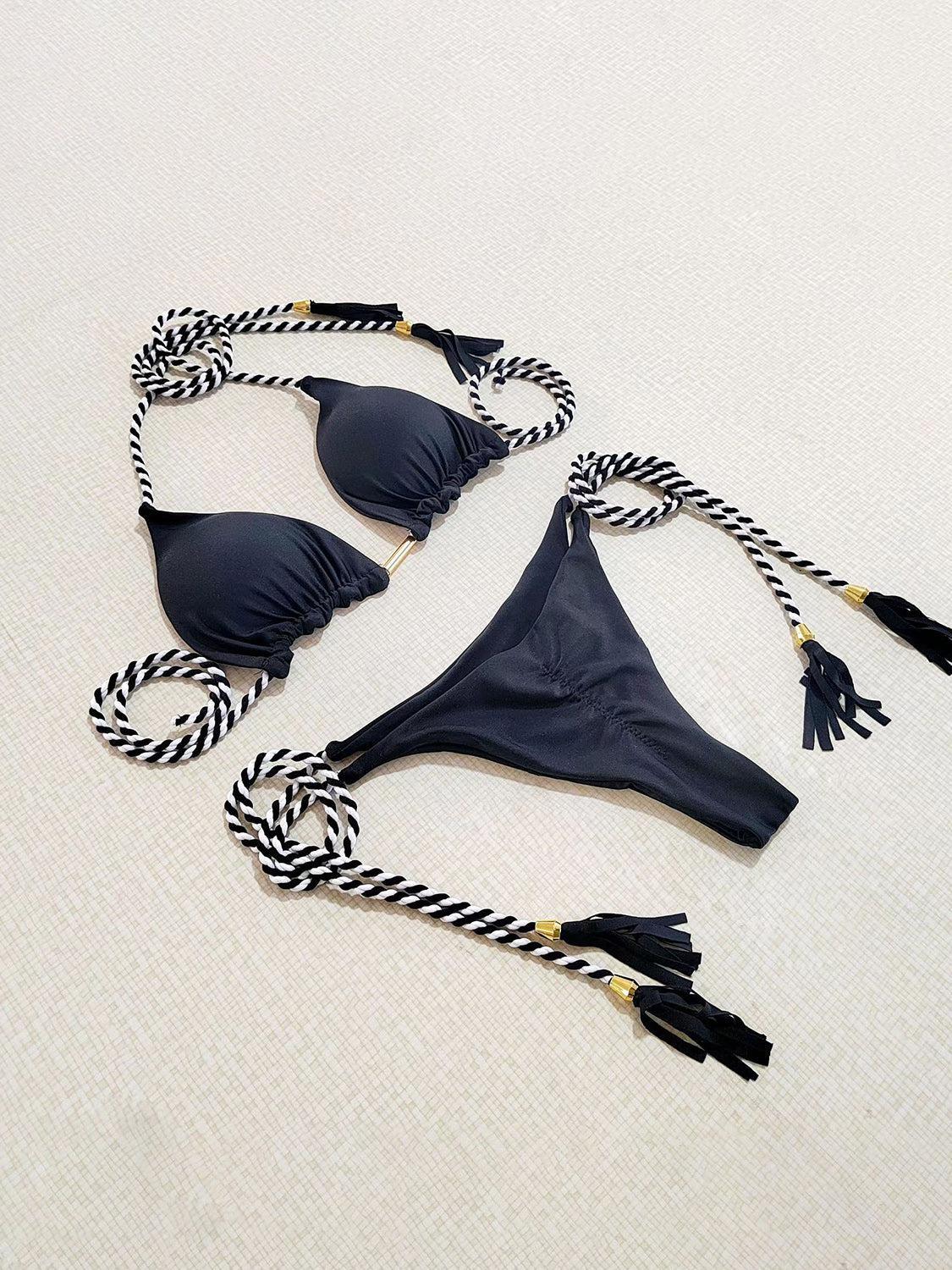 a black bikini top with tassels on a white surface