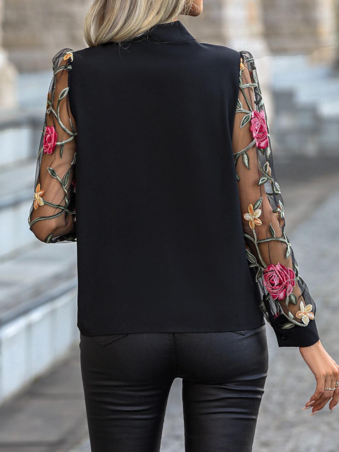 a woman wearing a black top with flowers on it