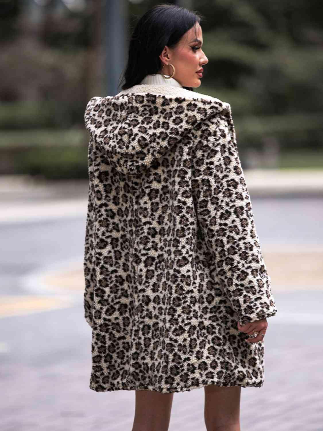a woman in a leopard print coat standing on a sidewalk